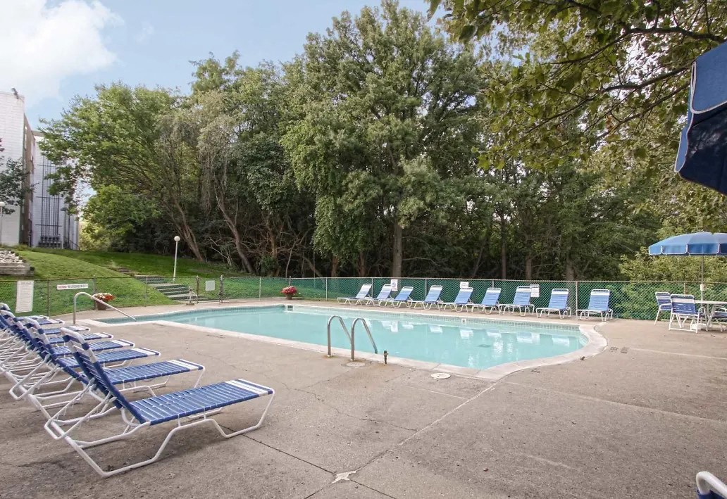 a resort style pool with blue and white chairs     and trees